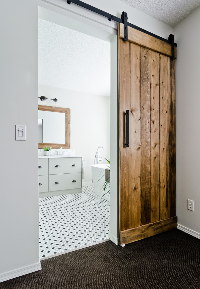 This is an example of a small transitional master bathroom in Calgary with flat-panel cabinets, grey cabinets, a freestanding tub, a curbless shower, a one-piece toilet, white tile, subway tile, grey walls, mosaic tile floors, an undermount sink, quartzite benchtops, black floor and a hinged shower door.