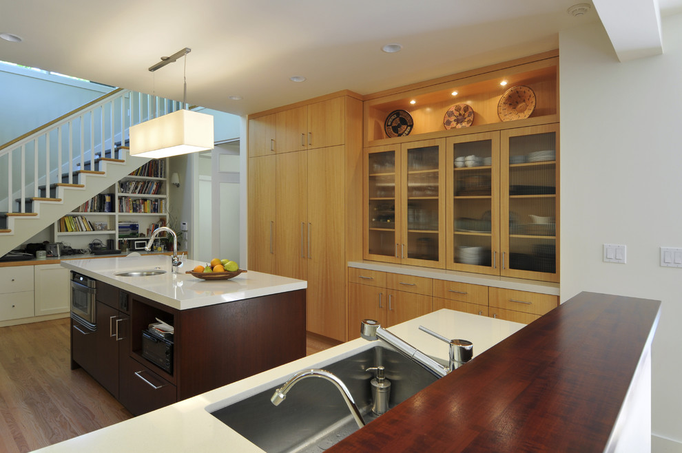 Inspiration for a contemporary l-shaped eat-in kitchen in San Francisco with an undermount sink, glass-front cabinets, medium wood cabinets, stainless steel appliances, medium hardwood floors and with island.