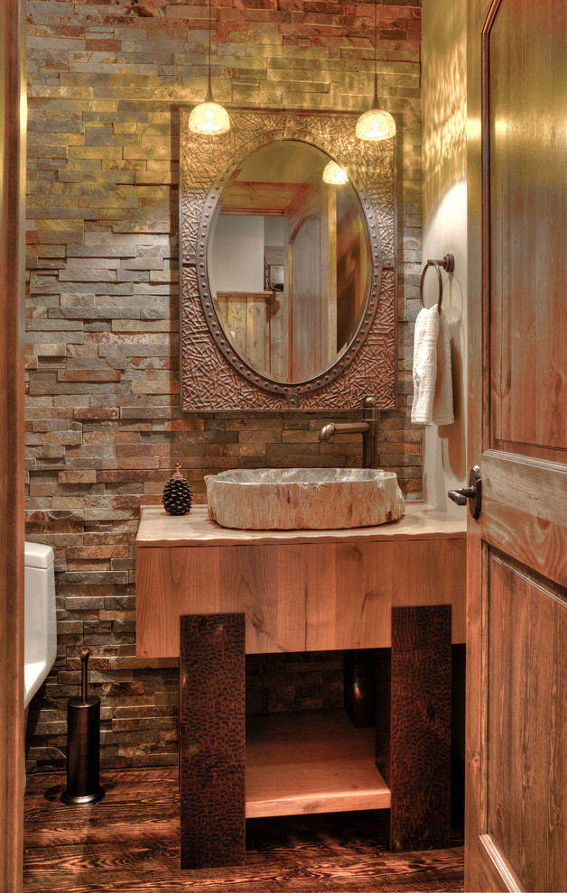 Photo of a country powder room in Minneapolis with dark hardwood floors, a vessel sink, flat-panel cabinets, medium wood cabinets and stone tile.
