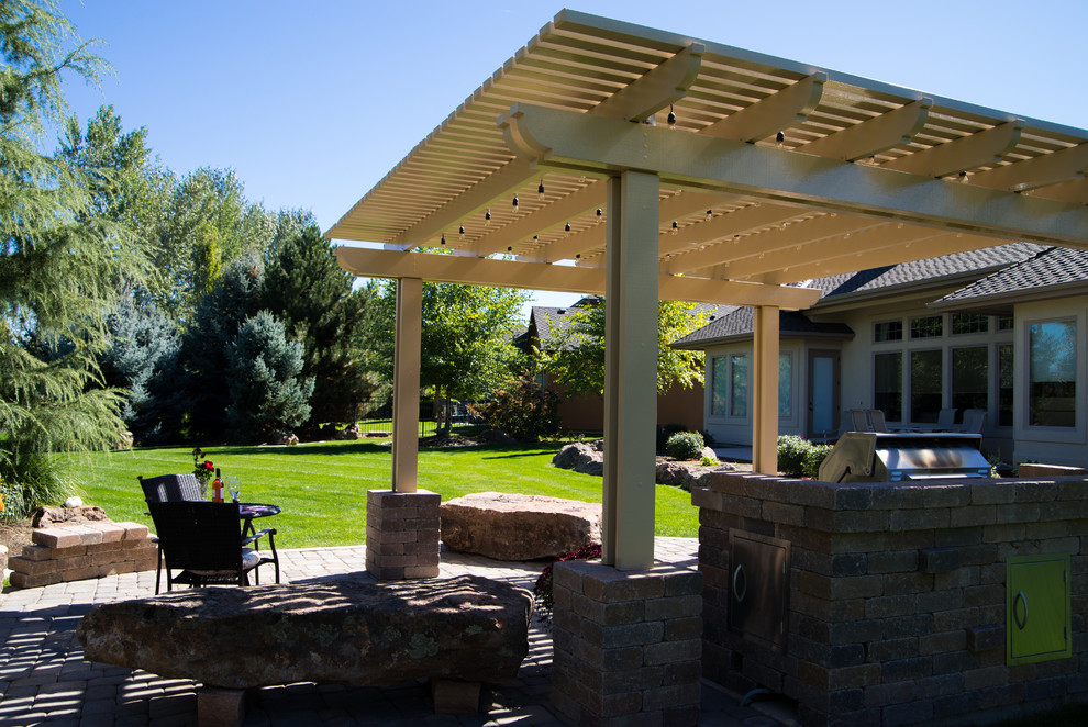 Photo of a midcentury backyard patio in Boise with an outdoor kitchen, natural stone pavers and a pergola.