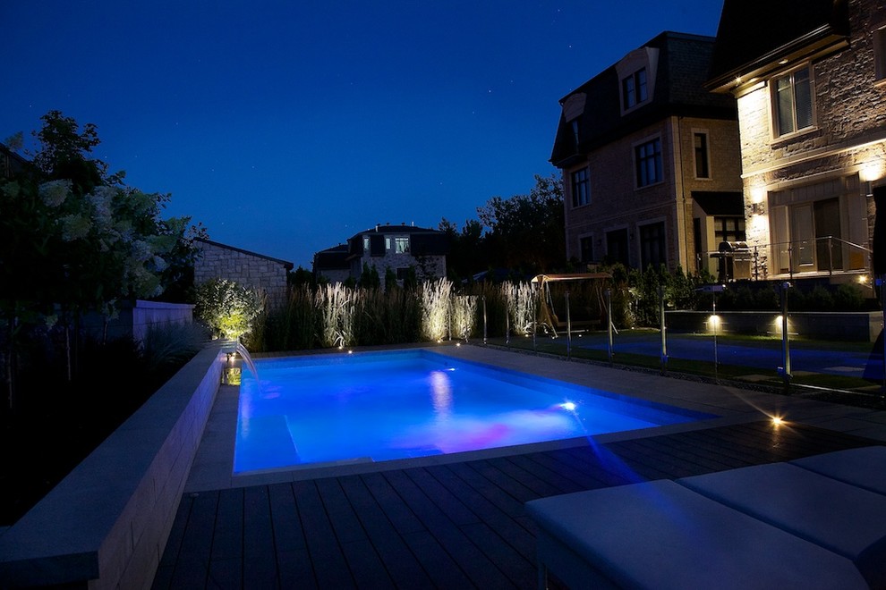 Diseño de casa de la piscina y piscina alargada tradicional renovada de tamaño medio rectangular en patio trasero con losas de hormigón