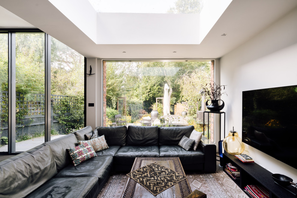 Eclectic open concept living room in London with white walls and a wall-mounted tv.