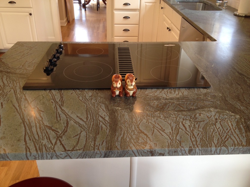 Example of a light wood floor kitchen design with soapstone countertops, white backsplash and ceramic backsplash