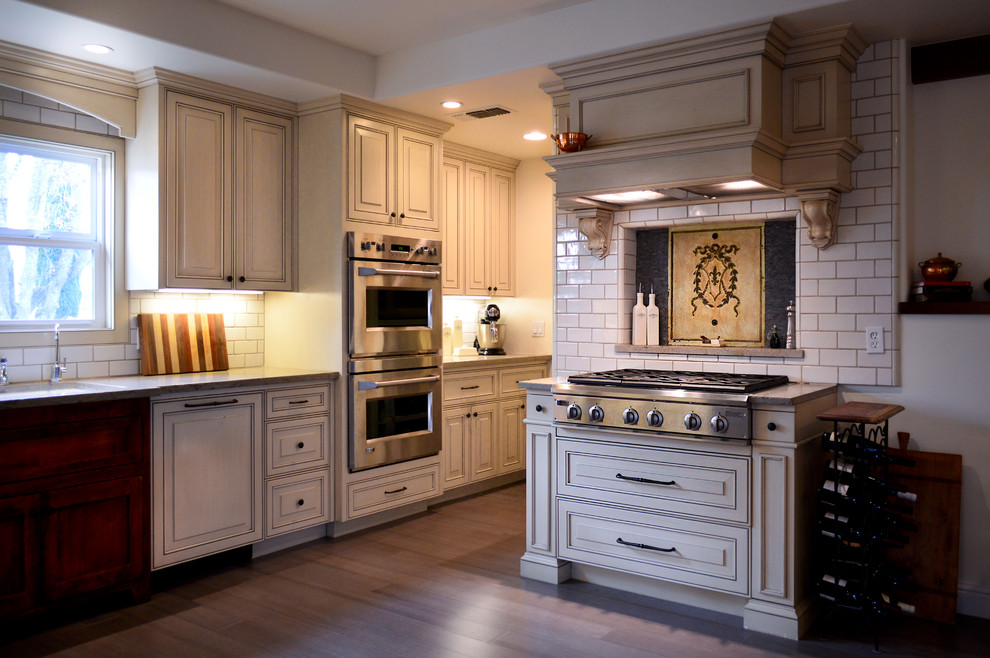 Country u-shaped separate kitchen in San Luis Obispo with an undermount sink, raised-panel cabinets, white cabinets, limestone benchtops, white splashback, subway tile splashback and stainless steel appliances.