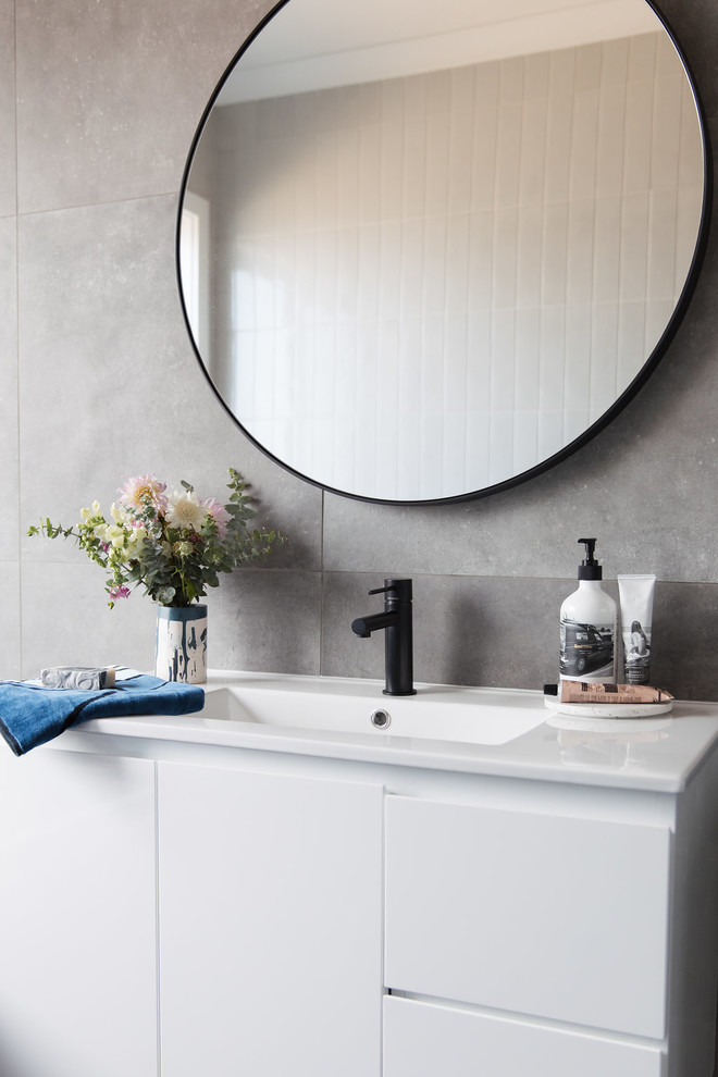 Mid-sized modern 3/4 bathroom in Canberra - Queanbeyan with furniture-like cabinets, white cabinets, a drop-in tub, gray tile, grey walls, an undermount sink, a one-piece toilet, porcelain tile, porcelain floors and grey floor.