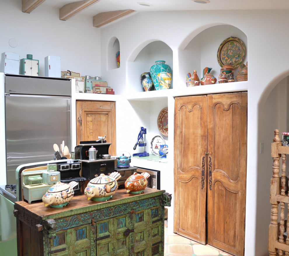 Photo of a mediterranean kitchen in Los Angeles with recessed-panel cabinets, light wood cabinets, wood benchtops, white splashback, porcelain floors and with island.