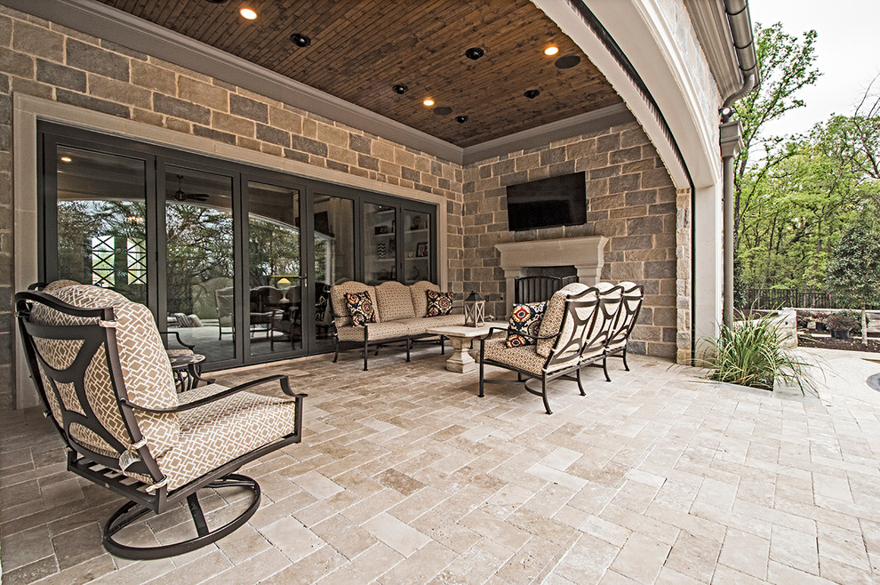 Photo of a large transitional patio in Dallas with natural stone pavers and a roof extension.