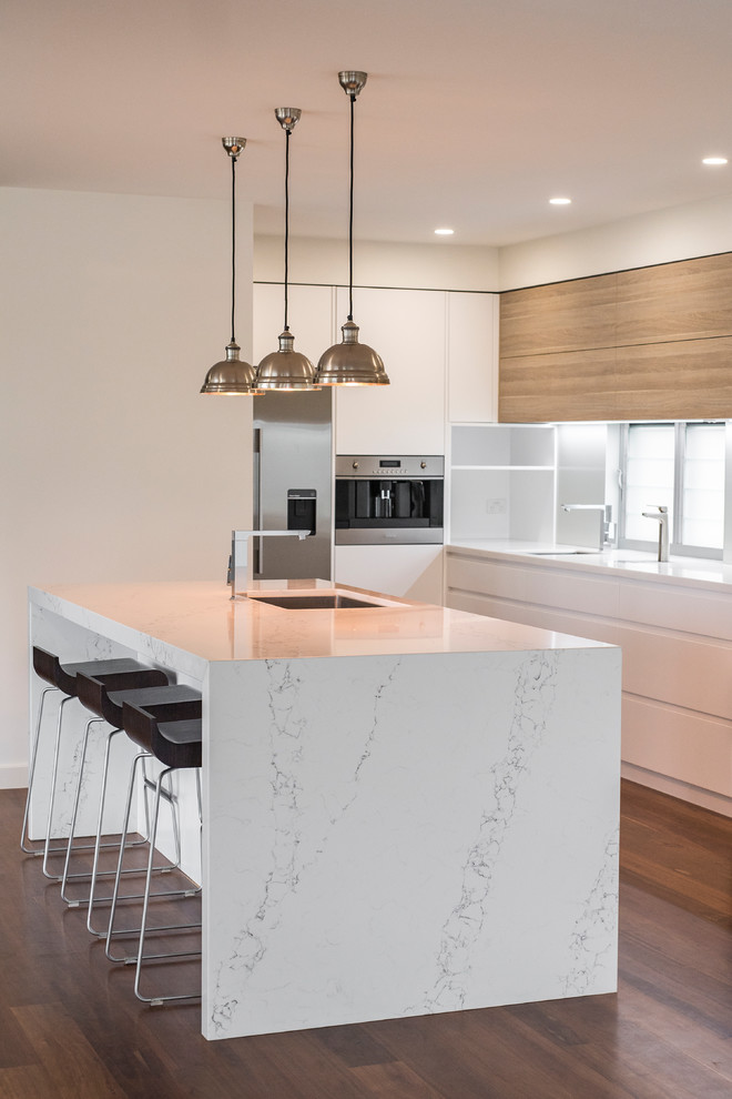 Large contemporary l-shaped eat-in kitchen in Newcastle - Maitland with an undermount sink, white cabinets, marble benchtops, white splashback, stainless steel appliances, with island, flat-panel cabinets and glass sheet splashback.