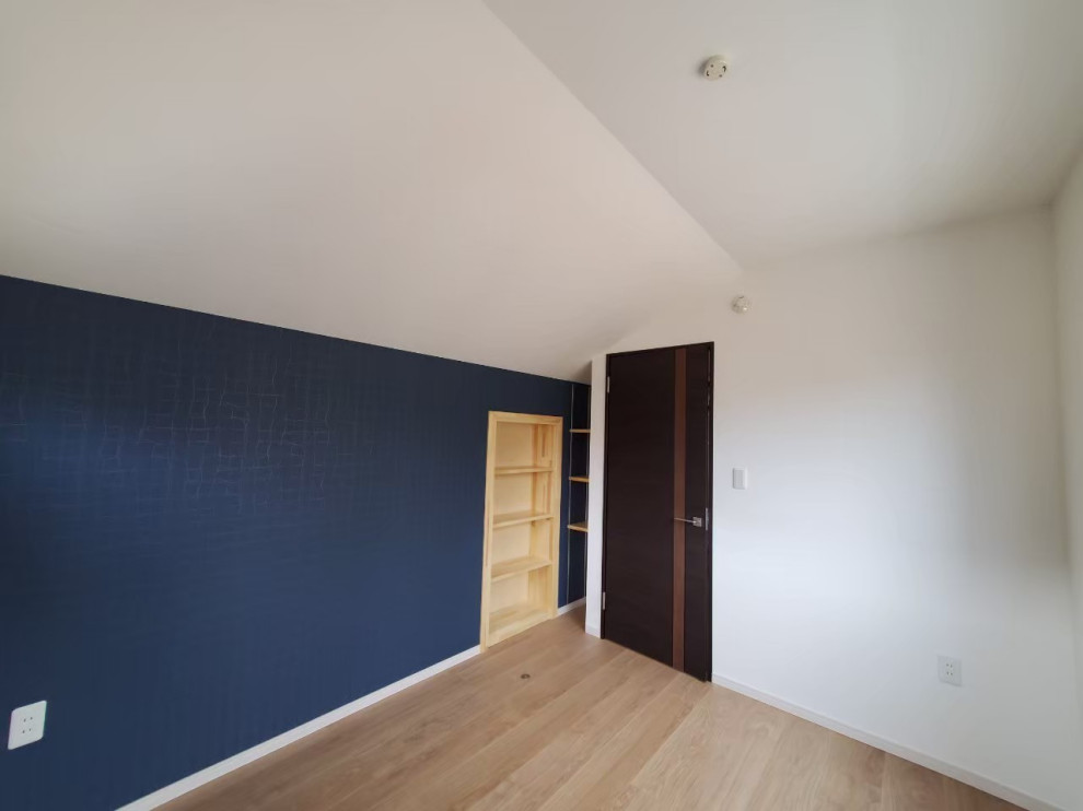 Cette image montre une chambre d'enfant minimaliste de taille moyenne avec un mur bleu, un sol en contreplaqué, un sol marron, un plafond en papier peint et du papier peint.