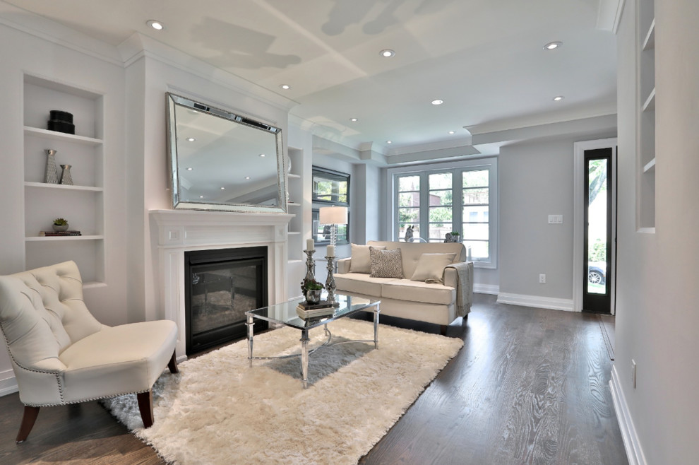 This is an example of a mid-sized contemporary formal open concept living room in Toronto with grey walls, medium hardwood floors, a standard fireplace, a plaster fireplace surround, no tv and brown floor.