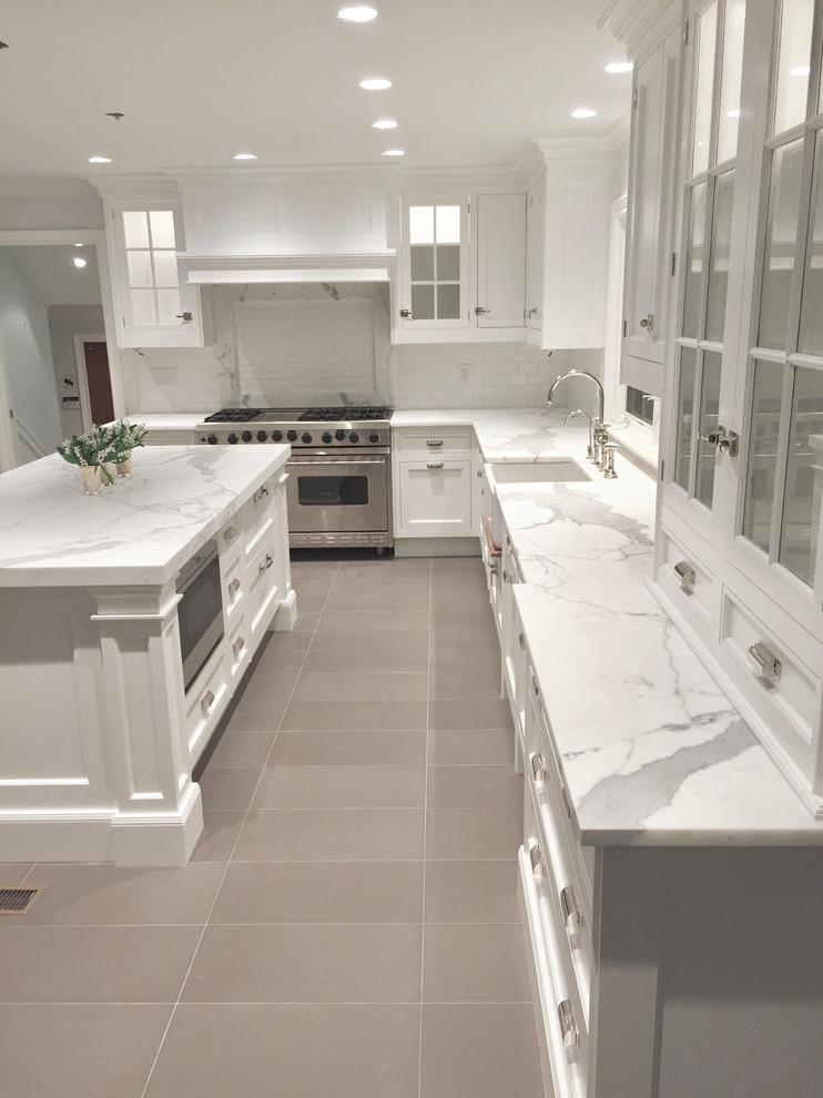 Large transitional l-shaped beige floor eat-in kitchen photo with a farmhouse sink, shaker cabinets, white cabinets, white backsplash, stainless steel appliances and an island