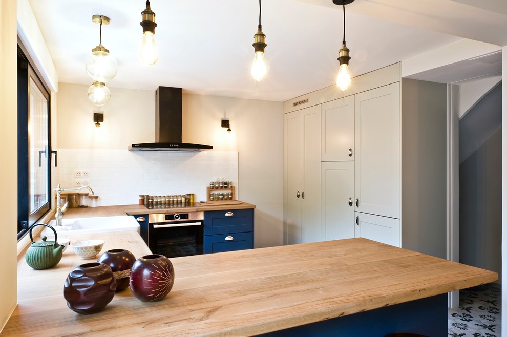 Mid-sized transitional u-shaped open plan kitchen in Paris with a drop-in sink, wood benchtops, white splashback, porcelain splashback, stainless steel appliances, cement tiles, no island, grey floor and yellow benchtop.