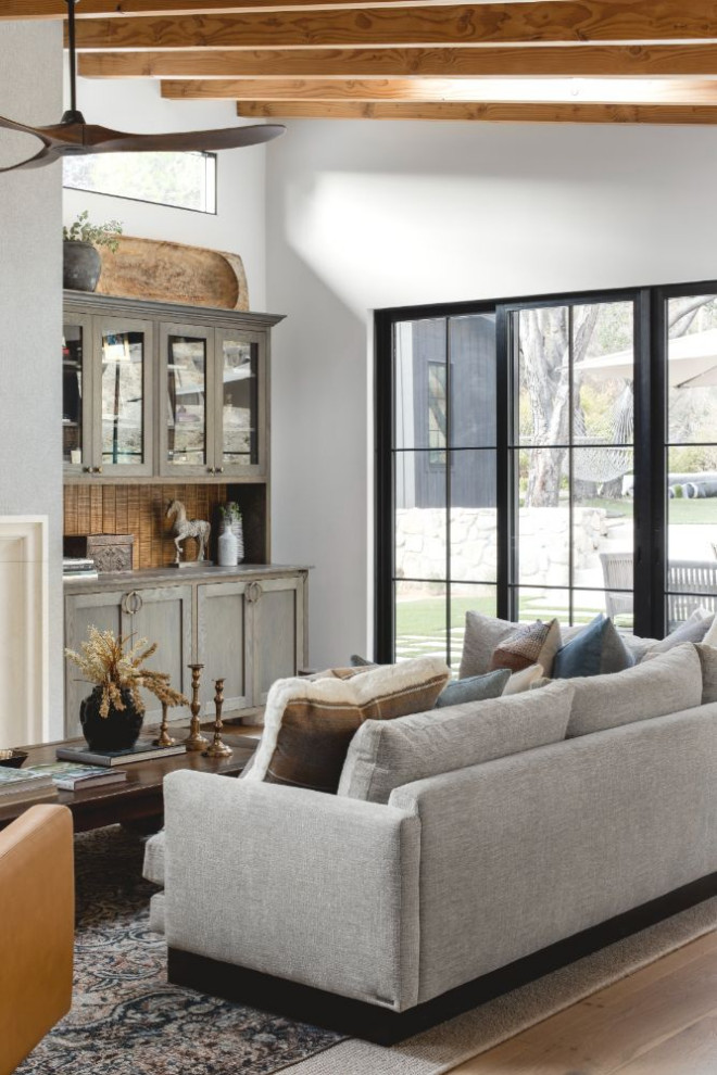 This is an example of a mid-sized contemporary formal open concept living room in Los Angeles with white walls, medium hardwood floors, a standard fireplace, a concrete fireplace surround and a wall-mounted tv.