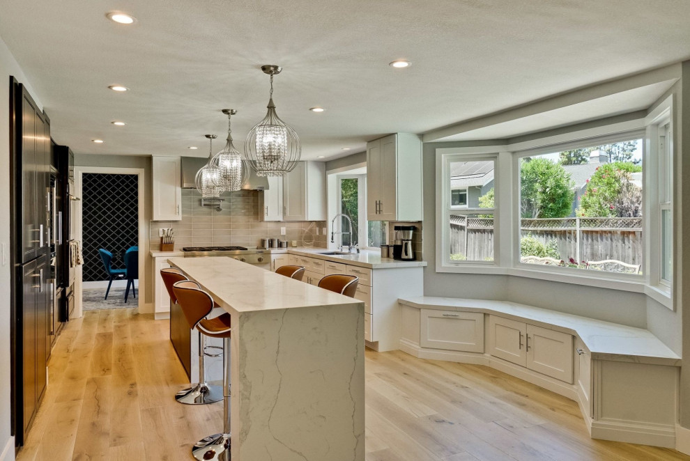 Large contemporary u-shaped open plan kitchen in San Francisco with an undermount sink, shaker cabinets, white cabinets, quartzite benchtops, grey splashback, glass tile splashback, stainless steel appliances, light hardwood floors, with island, beige floor and white benchtop.