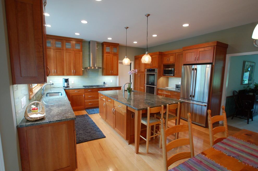 Inspiration for a large transitional u-shaped light wood floor and beige floor eat-in kitchen remodel in Cleveland with medium tone wood cabinets, granite countertops, glass tile backsplash, stainless steel appliances, gray walls, an island, an undermount sink, shaker cabinets and green backsplash