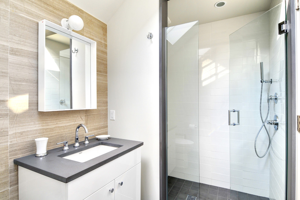 This is an example of a mid-sized contemporary 3/4 bathroom in Boston with an undermount sink, flat-panel cabinets, white cabinets, an alcove shower, white tile, a two-piece toilet, porcelain tile, white walls and concrete floors.