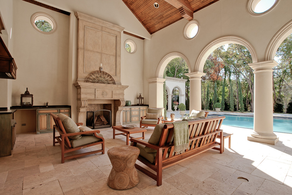 This is an example of a large mediterranean backyard patio in Dallas with natural stone pavers and with fireplace.