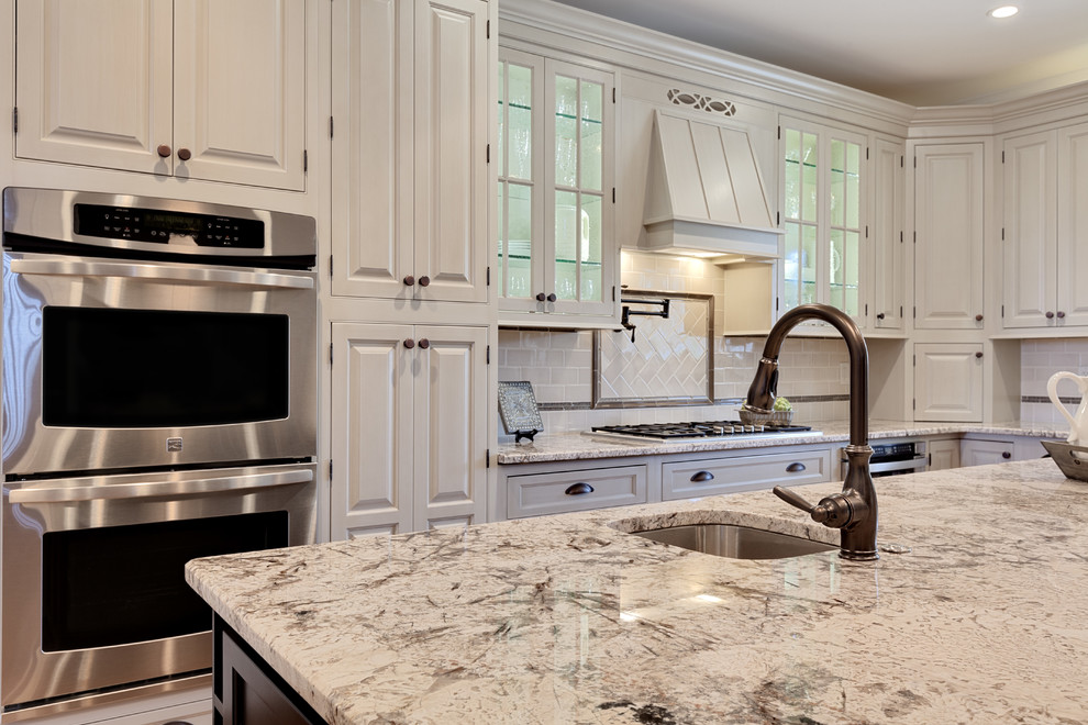 Design ideas for an expansive traditional l-shaped eat-in kitchen in Atlanta with a farmhouse sink, beaded inset cabinets, beige cabinets, granite benchtops, beige splashback, granite splashback, stainless steel appliances, medium hardwood floors, with island, brown floor and beige benchtop.