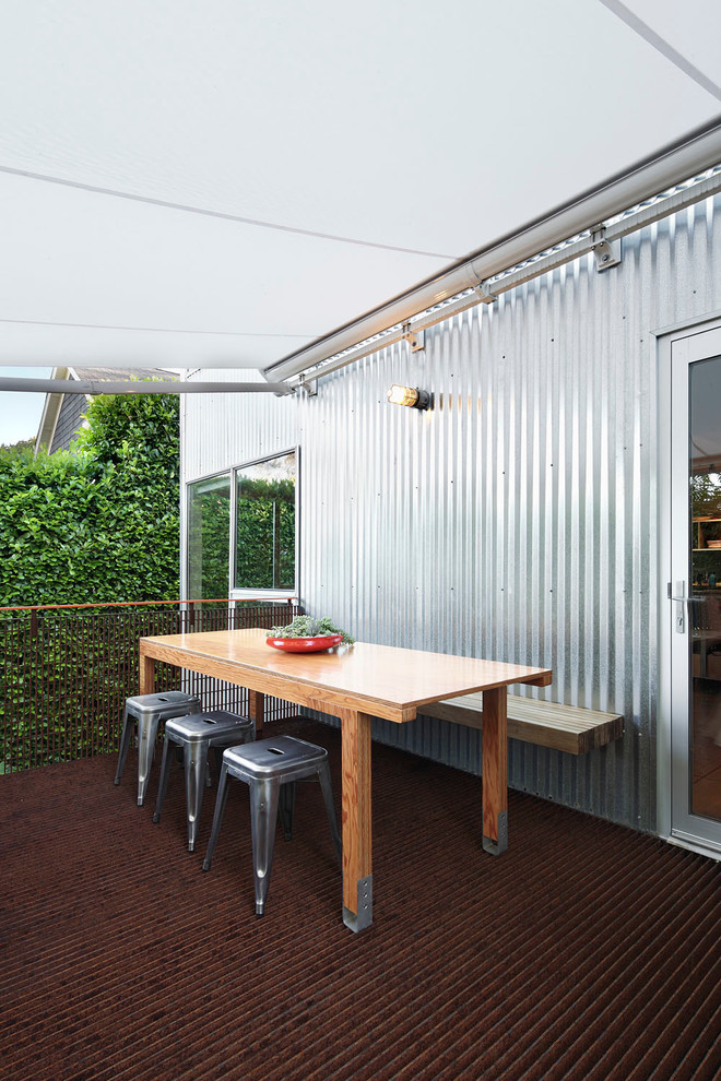 Photo of a mid-sized industrial backyard deck in Seattle with an awning.