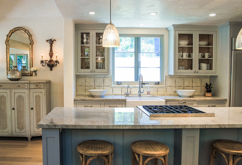 Inspiration for a traditional kitchen in Santa Barbara with a farmhouse sink, glass-front cabinets, grey cabinets, beige splashback and panelled appliances.