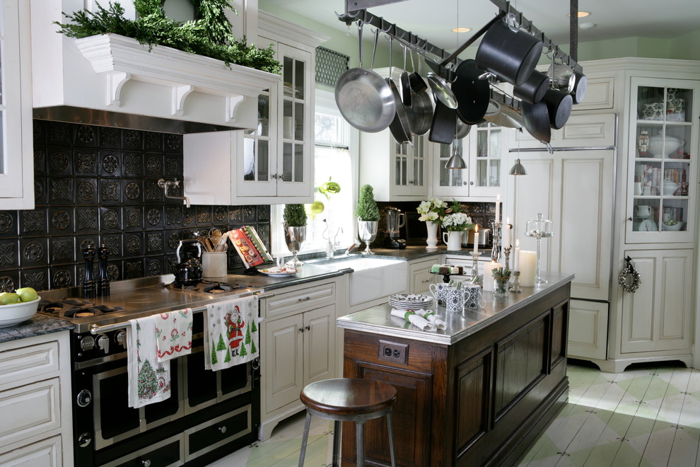 Traditional l-shaped separate kitchen in Chicago with a farmhouse sink, painted wood floors, with island, distressed cabinets, recessed-panel cabinets, black splashback, metal splashback and black appliances.