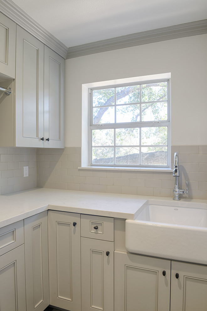 Inspiration for a small transitional l-shaped dedicated laundry room in Los Angeles with a farmhouse sink, beaded inset cabinets, beige cabinets, white walls, ceramic floors, a side-by-side washer and dryer, grey floor and white benchtop.