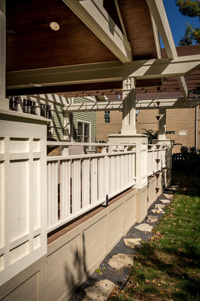This is an example of a large traditional front screened glass railing veranda in Chicago with natural stone paving and a roof extension.