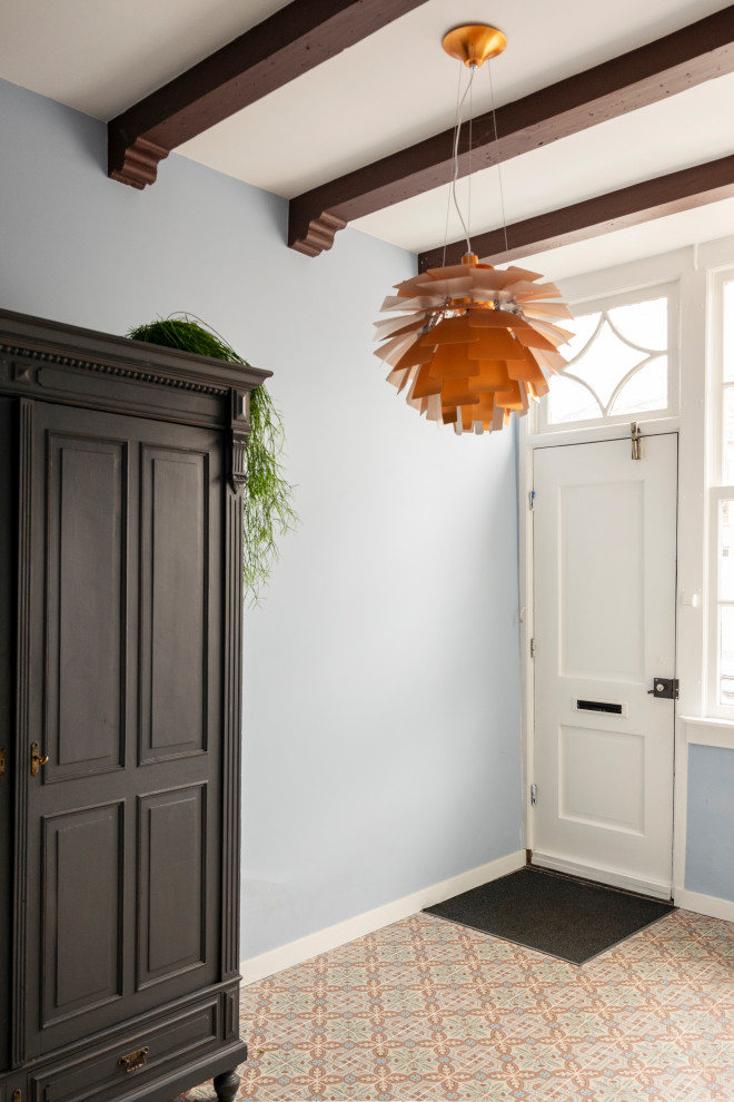 Foto di un piccolo ingresso o corridoio eclettico con pareti blu, pavimento con piastrelle in ceramica, pavimento multicolore e travi a vista