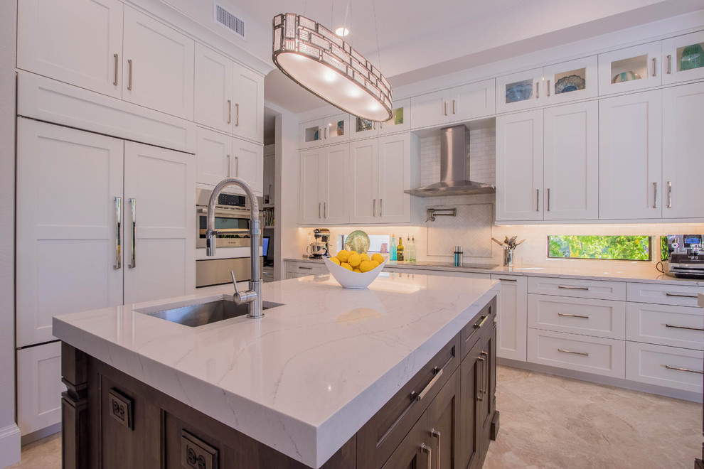 Open concept kitchen - huge transitional l-shaped porcelain tile and beige floor open concept kitchen idea with a farmhouse sink, shaker cabinets, white cabinets, quartz countertops, white backsplash, porcelain backsplash, stainless steel appliances and two islands
