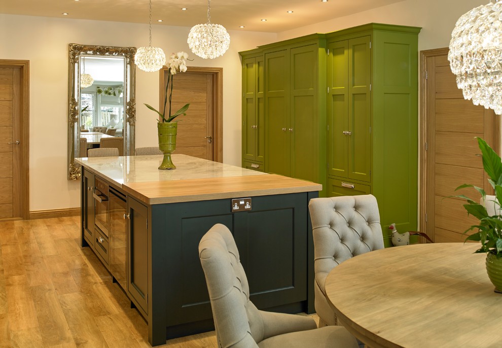 Large traditional single-wall eat-in kitchen in Other with a farmhouse sink, beaded inset cabinets, green cabinets, granite benchtops, green splashback, stone slab splashback, black appliances, medium hardwood floors, with island and green benchtop.