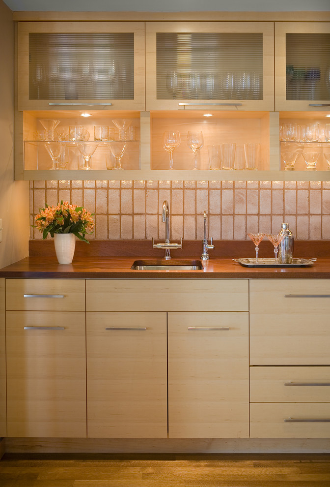 Photo of a contemporary single-wall kitchen in Minneapolis with flat-panel cabinets, light wood cabinets, wood benchtops, an undermount sink, white splashback and subway tile splashback.