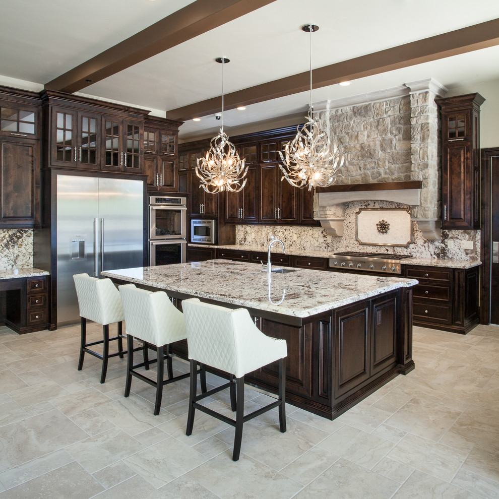 This is an example of a large mediterranean u-shaped open plan kitchen in Sacramento with an undermount sink, raised-panel cabinets, dark wood cabinets, granite benchtops, multi-coloured splashback, stone slab splashback, stainless steel appliances, travertine floors, with island and beige floor.