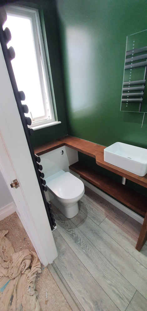 Small contemporary bathroom in Surrey with flat-panel cabinets, white cabinets, a walk-in shower, a one-piece toilet, green walls, laminate floors, a trough sink, wooden worktops, grey floors, a hinged door, brown worktops, a single sink and a built in vanity unit.