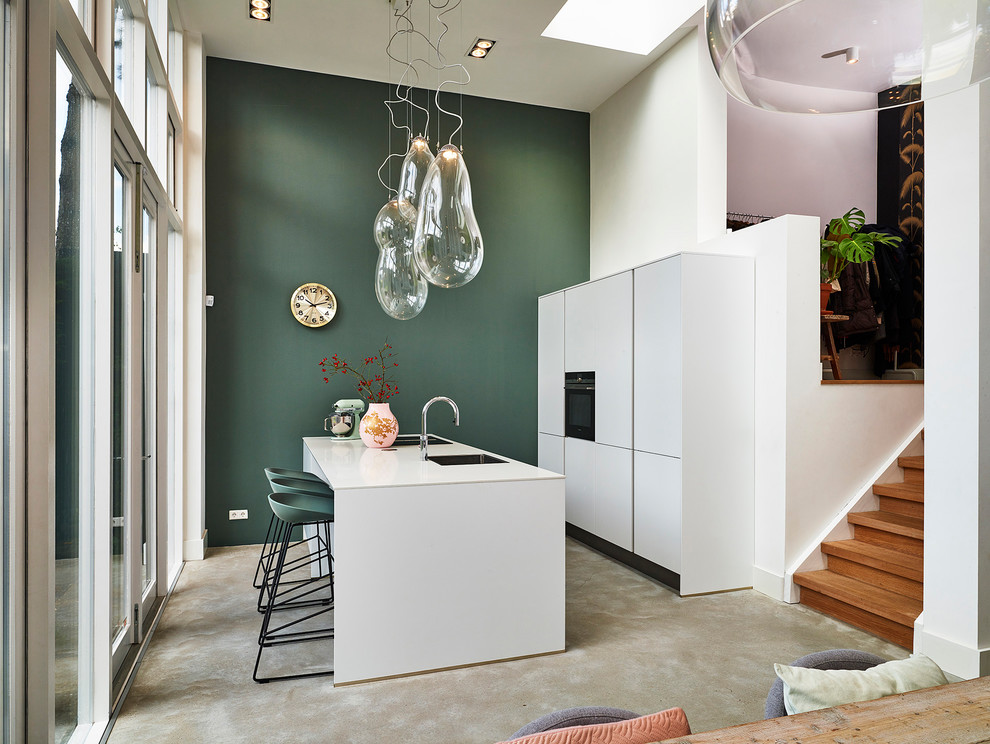This is an example of a mid-sized scandinavian galley eat-in kitchen in Other with flat-panel cabinets, white cabinets, with island, grey floor and white benchtop.