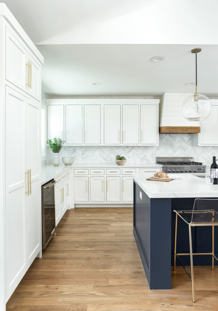 Design ideas for a large contemporary l-shaped open plan kitchen in Dallas with an undermount sink, shaker cabinets, white cabinets, quartz benchtops, white splashback, marble splashback, stainless steel appliances, light hardwood floors, with island, brown floor and white benchtop.