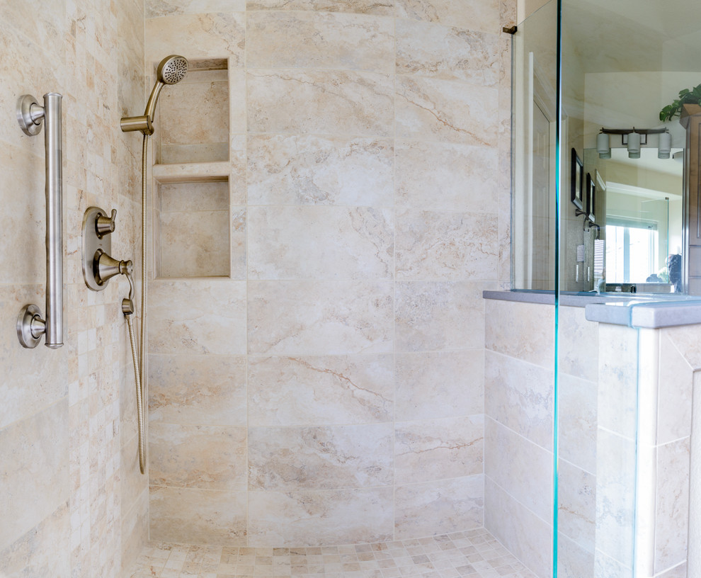 Example of a large transitional master beige tile and marble tile marble floor and beige floor corner shower design in Denver with raised-panel cabinets, dark wood cabinets, beige walls, an undermount sink, limestone countertops and a hinged shower door