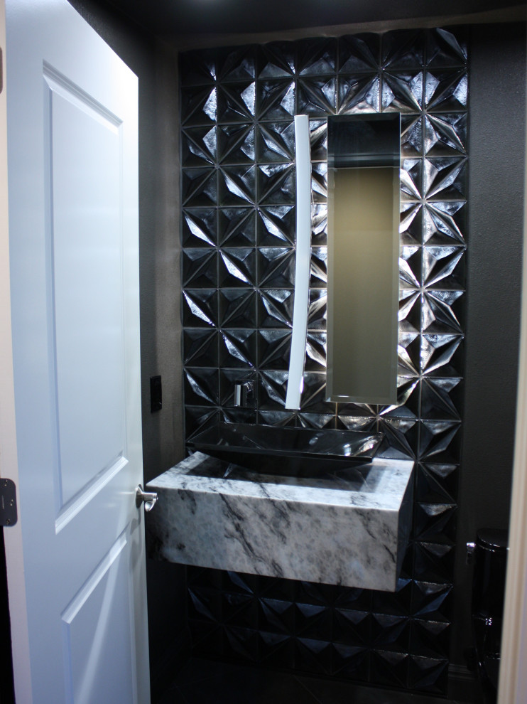 Photo of a small modern powder room in Tampa with black cabinets, a one-piece toilet, black tile, black walls, a vessel sink, white benchtops and a floating vanity.