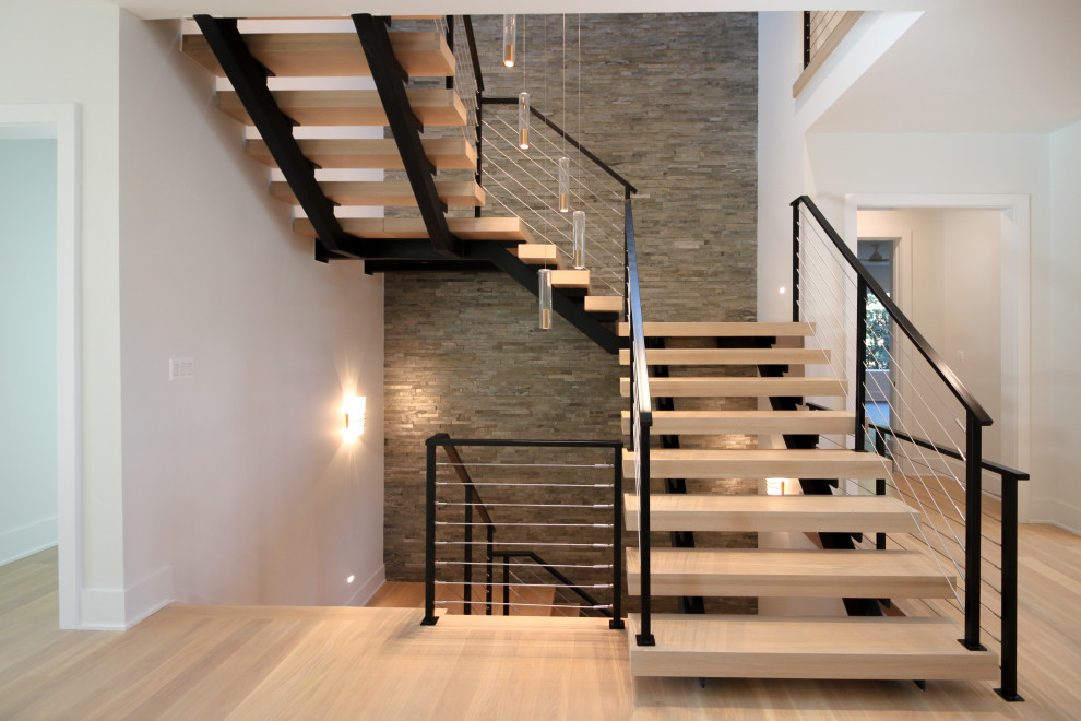 Foto de escalera suspendida ecléctica grande con escalones de madera, barandilla de metal y ladrillo