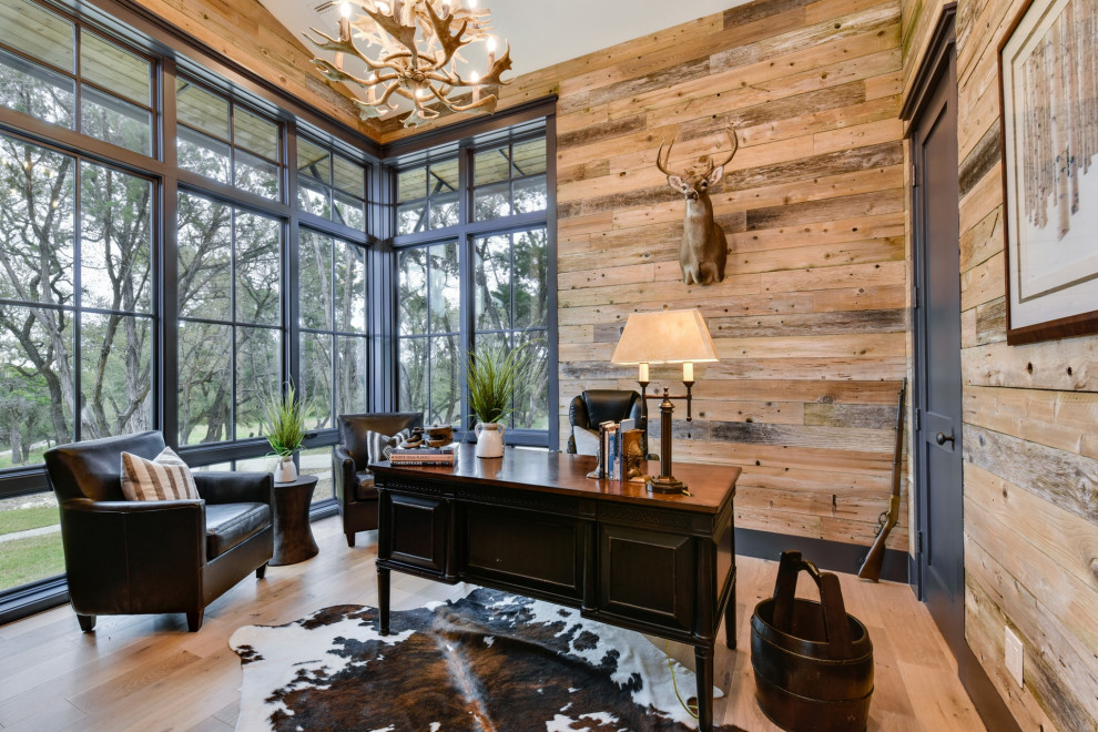 This is an example of a country home office in Austin with light hardwood floors, no fireplace, a freestanding desk, vaulted and wood walls.