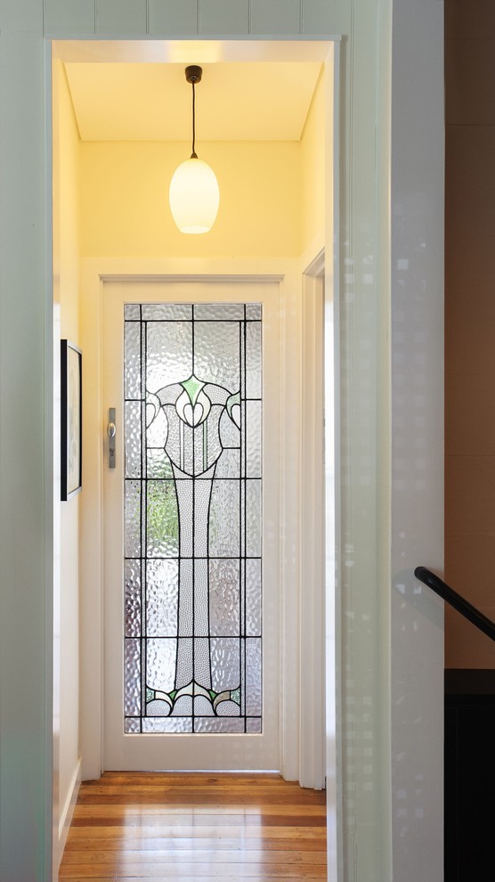 This is an example of a mid-sized contemporary hallway in Brisbane with white walls, medium hardwood floors and brown floor.