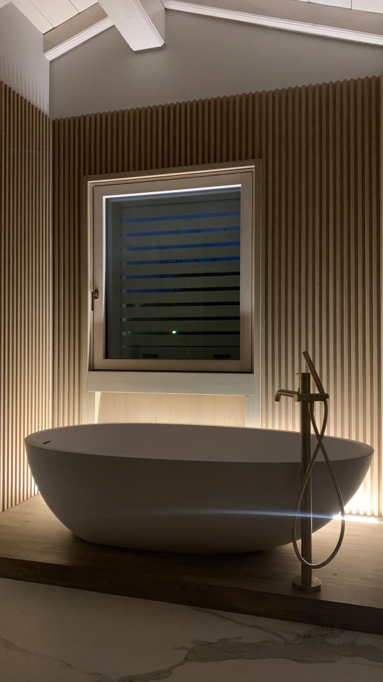 This is an example of a small contemporary 3/4 bathroom in Milan with glass-front cabinets, beige cabinets, a freestanding tub, a curbless shower, a wall-mount toilet, white tile, porcelain tile, porcelain floors, marble benchtops, white floor, a hinged shower door, brown benchtops, a single vanity, a floating vanity, exposed beam, decorative wall panelling, beige walls, an integrated sink and a shower seat.