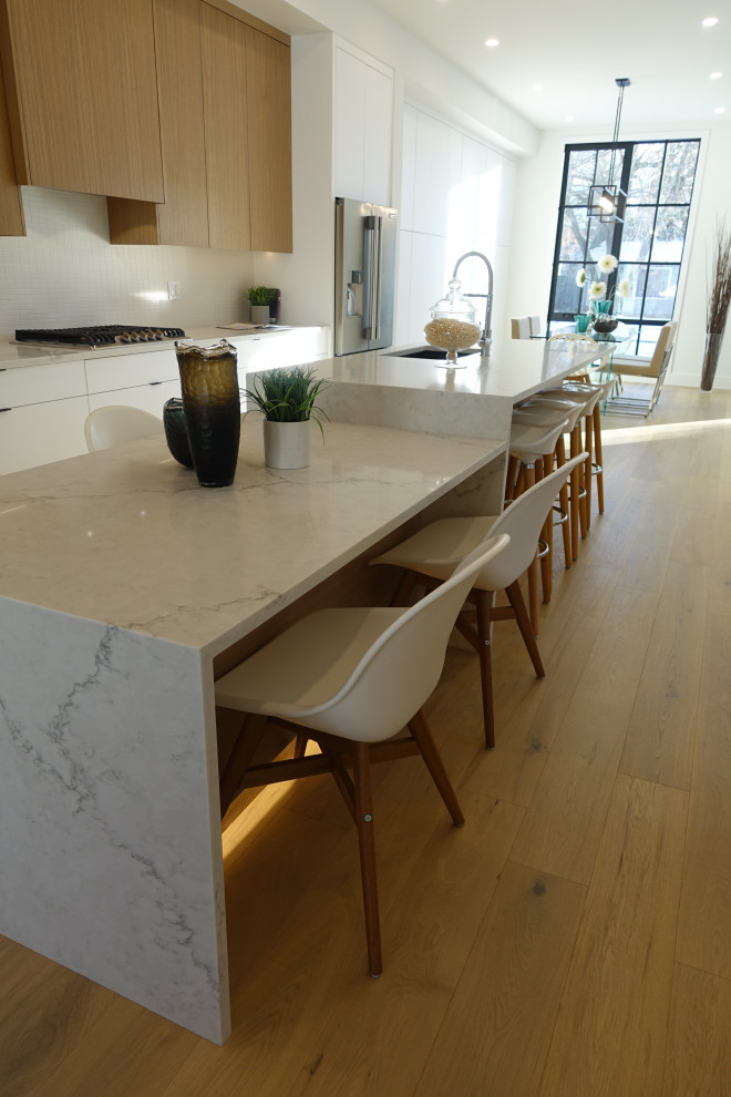 Eat-in kitchen - small transitional single-wall medium tone wood floor, white floor and tray ceiling eat-in kitchen idea in Calgary with a double-bowl sink, flat-panel cabinets, white cabinets, quartz countertops, white backsplash, stone tile backsplash, colored appliances, two islands and white countertops