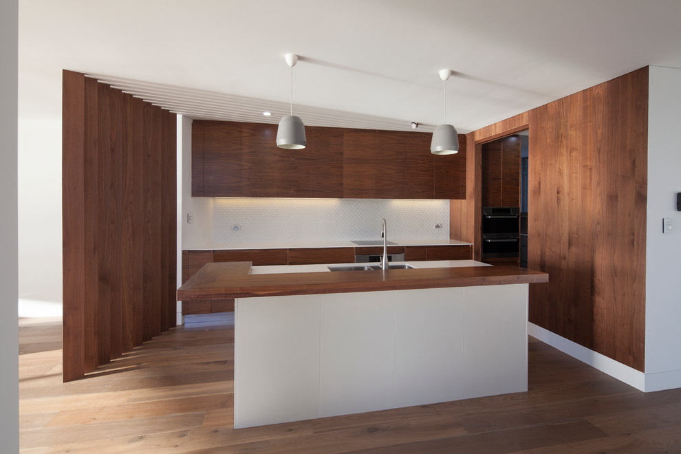 Design ideas for a large contemporary galley eat-in kitchen in Sydney with an integrated sink, medium wood cabinets, granite benchtops, white splashback, ceramic splashback, stainless steel appliances, medium hardwood floors and with island.