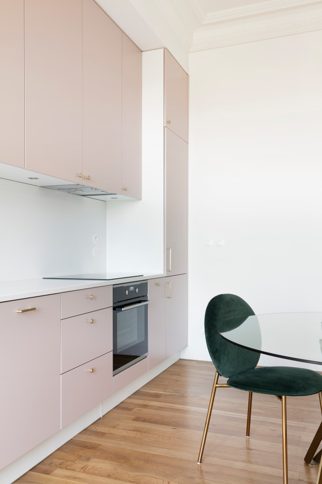 Inspiration för mellanstora moderna linjära vitt kök med öppen planlösning, med en undermonterad diskho, bänkskiva i kvartsit, vitt stänkskydd, svarta vitvaror, ljust trägolv, luckor med profilerade fronter och brunt golv