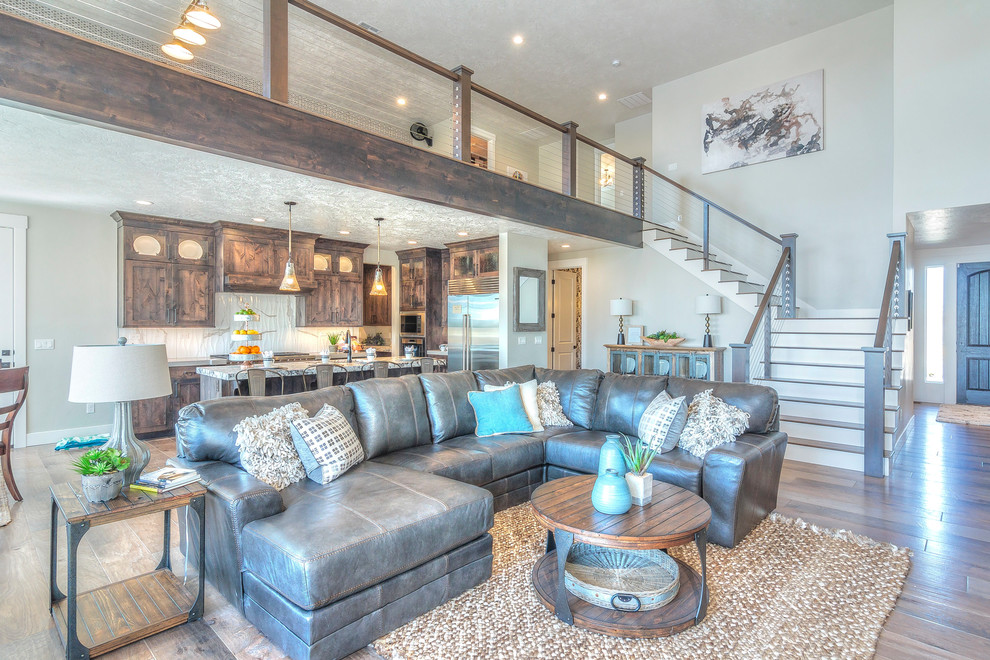 This is an example of a large arts and crafts formal open concept living room in Boise with grey walls, dark hardwood floors, brown floor, a standard fireplace, a stone fireplace surround and a wall-mounted tv.