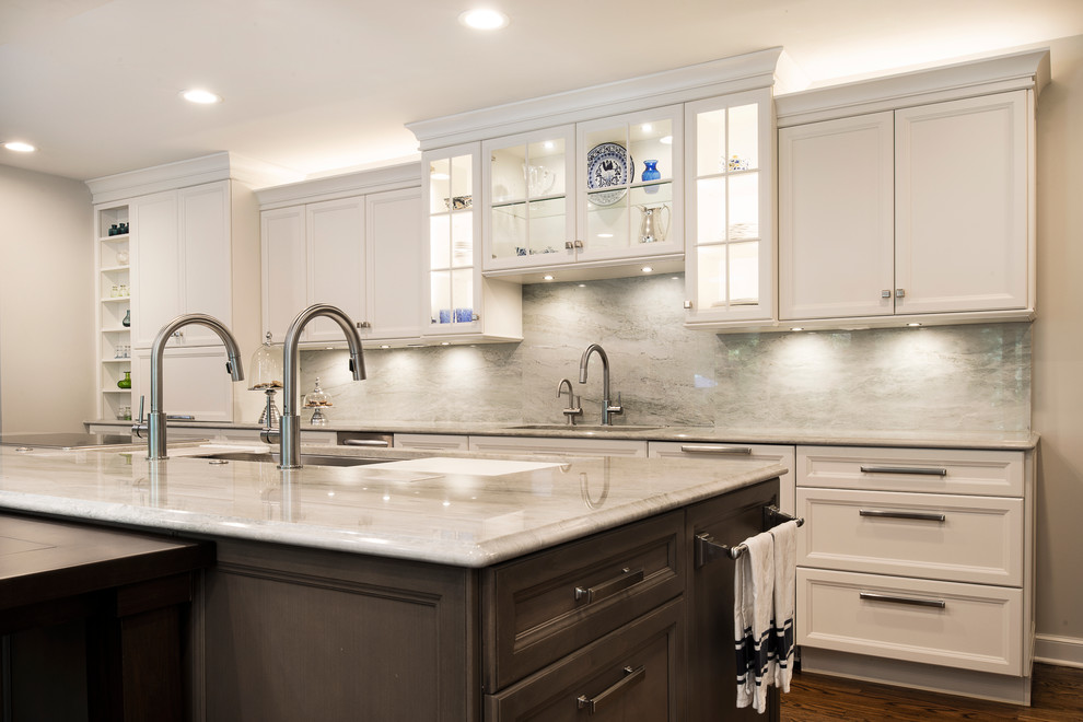Inspiration for a large transitional single-wall medium tone wood floor and brown floor kitchen remodel in Denver with an undermount sink, recessed-panel cabinets, white cabinets, white backsplash, stone slab backsplash, stainless steel appliances and an island