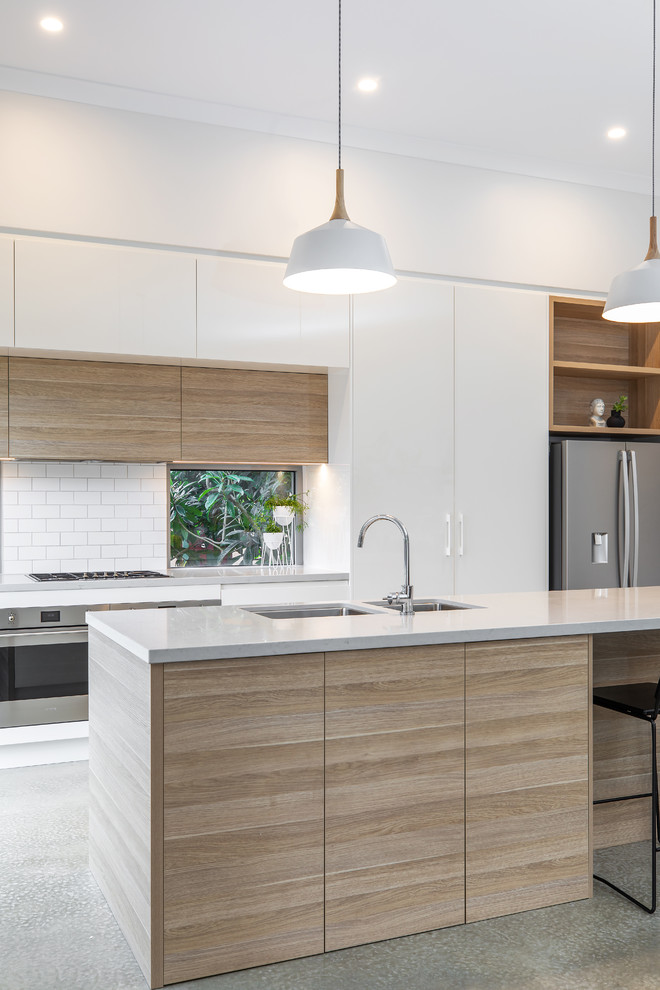 Inspiration for a mid-sized contemporary galley kitchen pantry in Adelaide with an undermount sink, flat-panel cabinets, light wood cabinets, quartz benchtops, white splashback, subway tile splashback, stainless steel appliances, concrete floors, with island, grey floor and grey benchtop.
