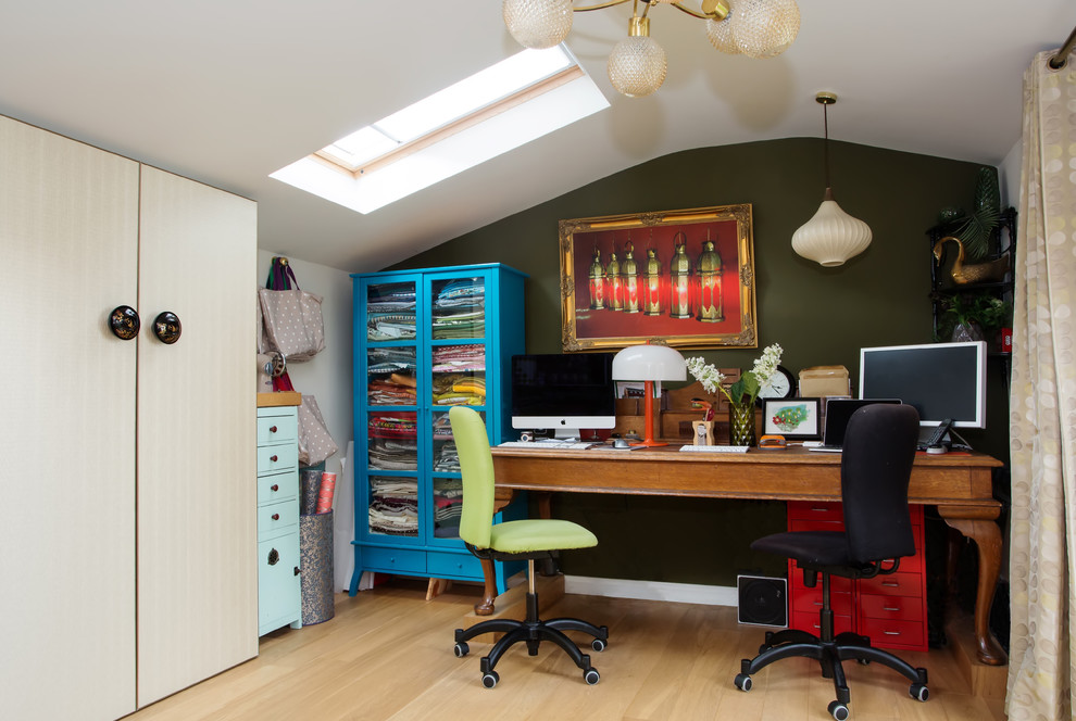 This is an example of an eclectic study room in Berkshire with green walls and a freestanding desk.
