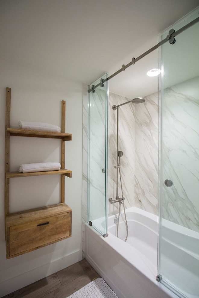 Inspiration for a mid-sized modern master bathroom in Austin with open cabinets, medium wood cabinets, an alcove tub, a shower/bathtub combo, white tile, stone slab, white walls, laminate floors, brown floor and a sliding shower screen.