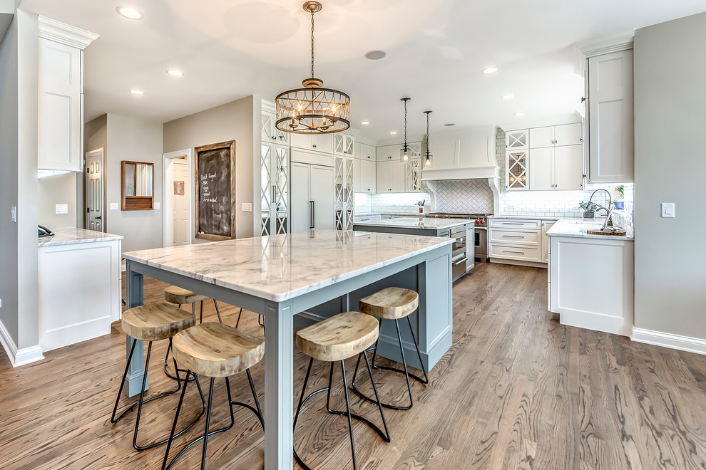 Example of a transitional open concept kitchen design in Chicago with white backsplash, subway tile backsplash and two islands
